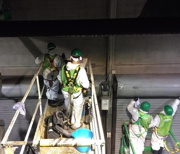 Men in biohazard suits cleaning a warehouse
