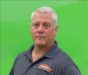 Male employee with gray hair standing in front of green background
